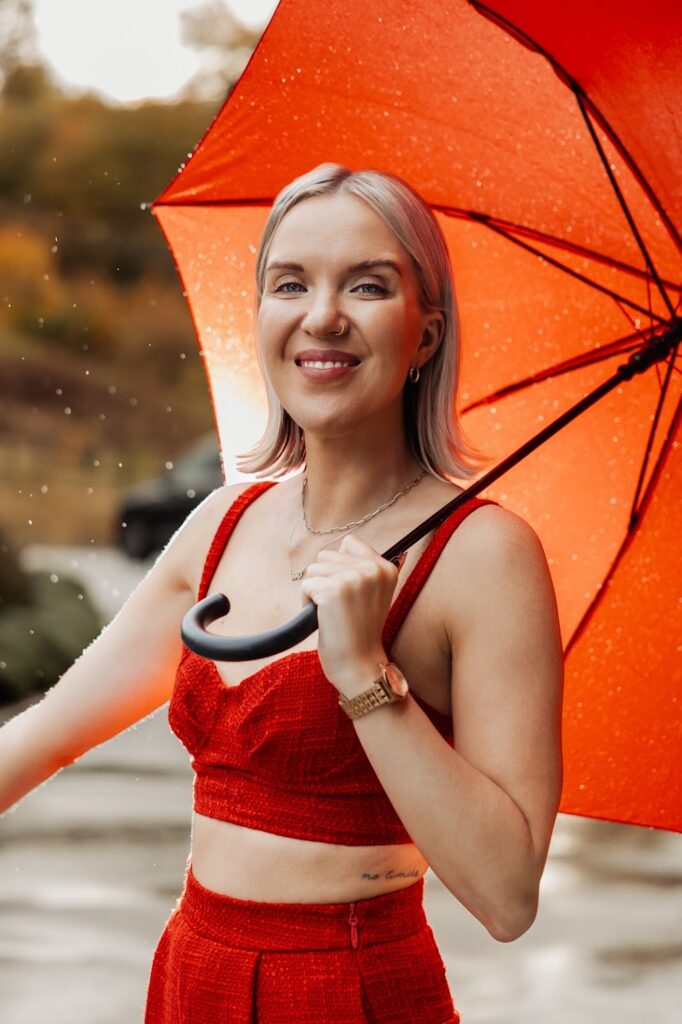 Public relations expert Katrina Owens smiles at the camera in a red two-piece outfit under a red umbrella