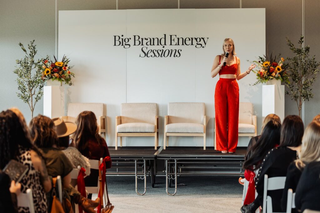 Personal Branding Coach Katrina Owens stands on stage in a two-piece red outfit to discuss building a personal brand to entrepreneurs and industry leaders