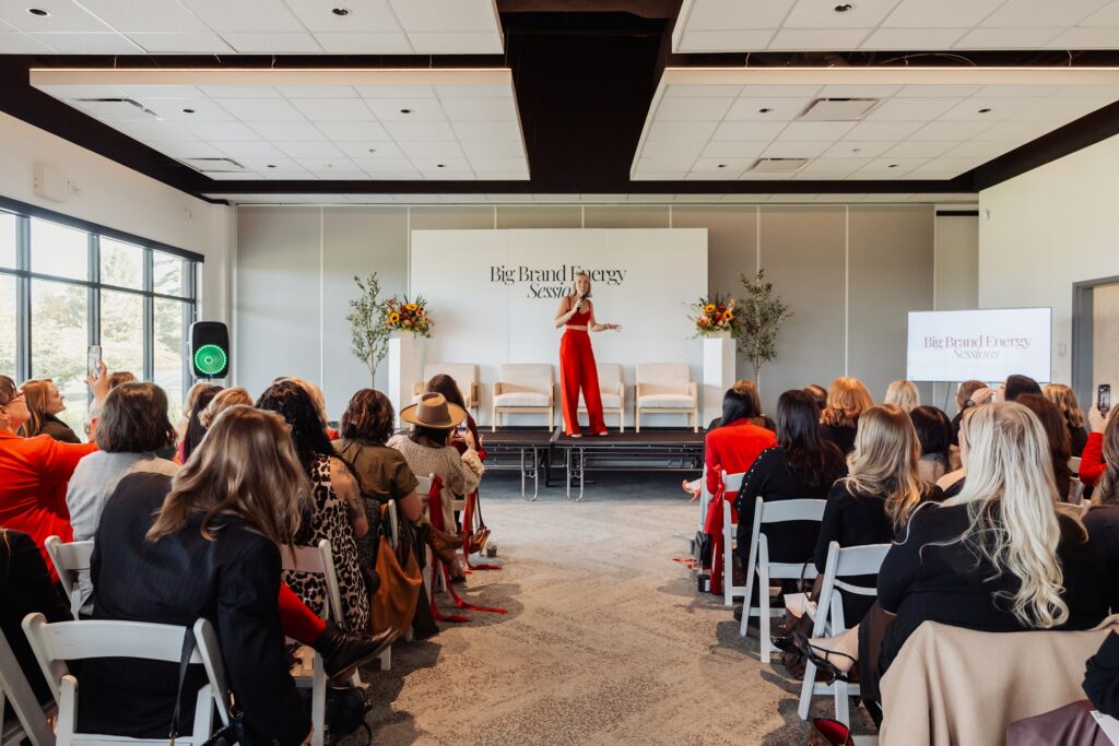 Public Relations for Executives expert Katrina Owens speaks about creating a personal brand to an audience in a two-piece red outfit on stage