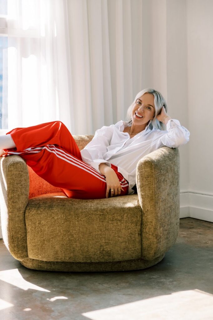 Visibility expert Katrina Owens sits in a chair smiling at the camera for a brand photoshoot as part of her 90-Day Visibility Sprint strategy