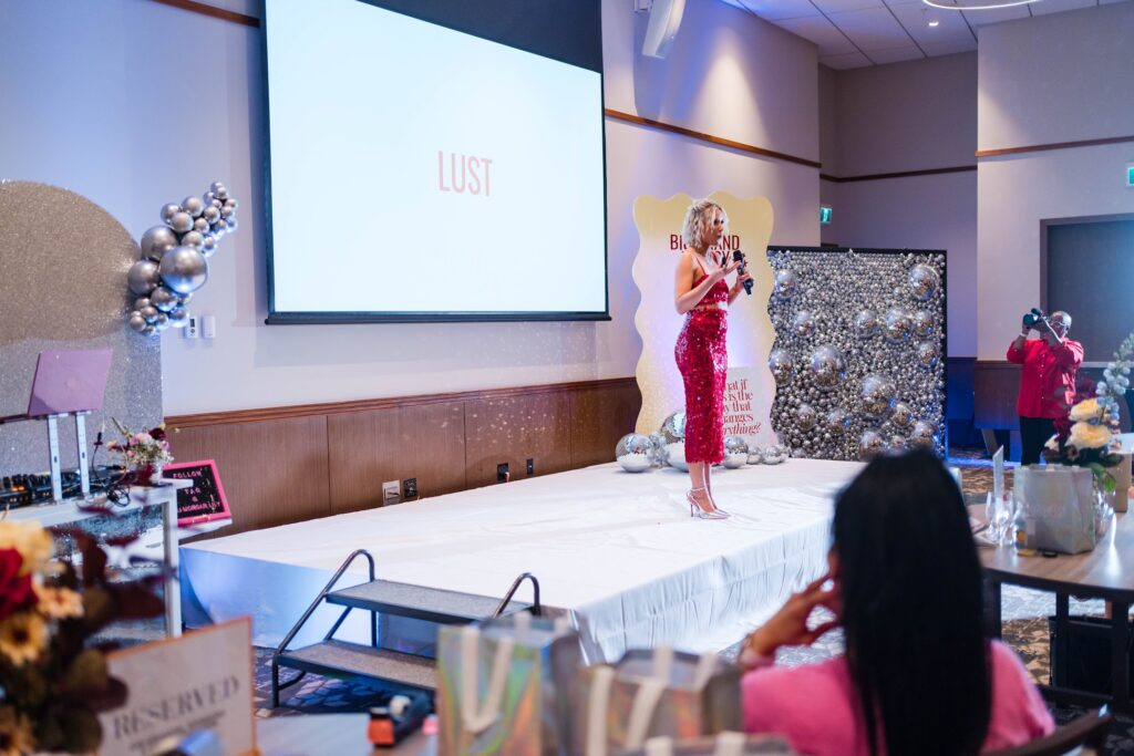executive keynote speaker Katrina Owens inspires audiences about personal branding on stage in a signature red outfit