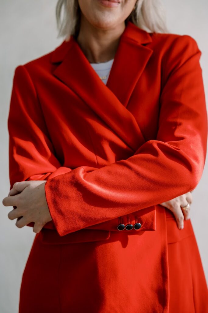 A close-up shot of Personal brand and online visibility expert Katrina Owens, mostly her red blazer with her arms crossed over her chest