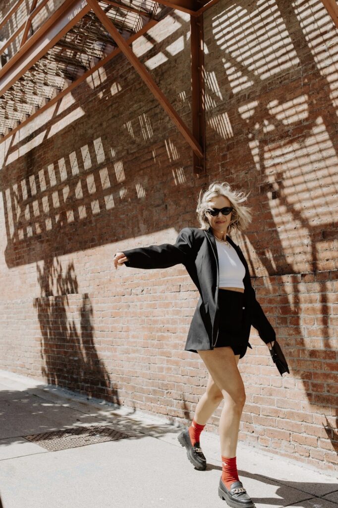 Paid PR expert Katrina Owens stands in front of a brick wall smiling during a photoshoot to support paid PR strategies